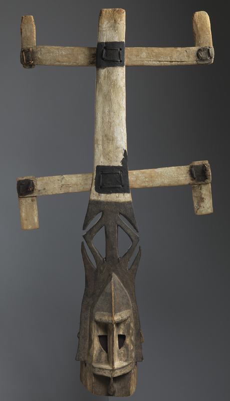 The Dogon migrated to present-day Mali beginning in the fifteenth century, settling along the Bandiagara escarpment. The harsh, remote terrain of central Mali protected the Dogon and shaped their culture. The Kanaga mask honors the dead and connects them to the living, in much the same way as the long cliff on which they live connects the earth and sky, and the vertical strip of the mask connects the two horizontal bands. Young men wear the Kanaga mask during the Dama ceremony, a funeral festival that occurs every twelve years in which the masks lead those who died during the cycle to the afterlife. The masks are painted with white, black, and often washer&#039;s blue, a chalky material traditionally used to whiten clothes in the laundry. A brightly colored raffia mane surrounds the face and complements the raffia bands along the arms and feet of the dancer. The dancer also wears a kilt and suspenders. The masquerader secures the mask by biting down on a bit, though there is netting in the back to keep it upright. Though the wood is not heavy, his dance includes whipping his body around and scraping the tip of the mask to the earth, making it a dynamic and audible procession.