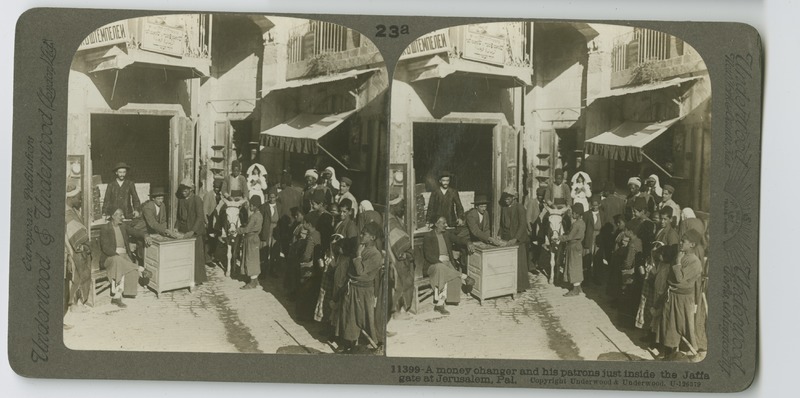 A money changer&#039;s shop near the Jaffa Gate in Jerusalem, showing a line of waiting patrons.