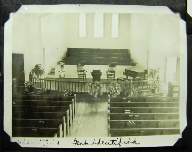 The interior of a sanctuary looking towards the pulpit and chior from behind the rows of pews.
