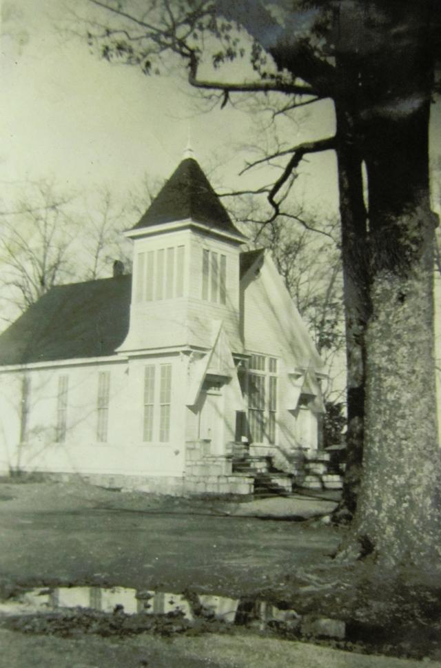 An unidentified church building with a view of the front door beneath the steeple and the large front window.