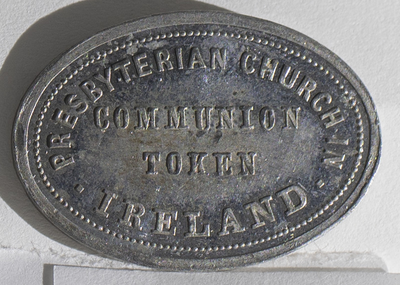 A communion token from the Presbyterian Church of Ireland. The token is oval shaped with inscriptions on the obverse, &quot;Presbyterian Church in Ireland Communion Token&quot;, and reverse, &quot;Do This in Remembrance of Me I. Cor.XI.24 But Let a Man Examine Himself&quot;.